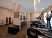 A gym with treadmills, an elliptical, a wall of kettlebells, and a hydration station under bright ceiling lights.