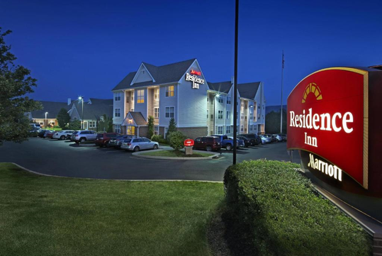 Exterior view of Residence Inn by Marriott at night, with well-lit signage, several parked cars, and manicured landscaping.