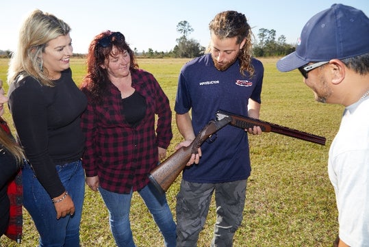 An instructor shows guests the inside of the gun used for clay shooting