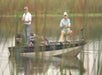 Two men on a boat, holding fishing poles