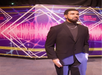 Wax figure of a man in a suit and turtleneck with a chain, set against a vibrant geometric and waveform backdrop at Louis Tussaud's Waxworks.