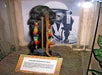 A genuine shrunken head with very long hair on display with a black and white photo behind it at Ripley's Believe It or Not! Orlando Odditorium.
