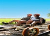 Two people wearing helmets ride a pedal-powered cart on railway tracks under a clear blue sky.