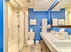 Fresh towels, complimentary toiletries, double-sink vanity and a glass-enclosed shower inside a private bathroom.
