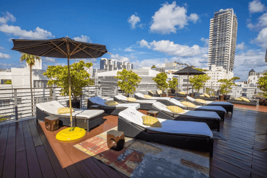 Roof deck with sun loungers and pool umbrella at Riviera Suites, FL.