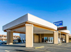 Exterior view of a Rodeway Inn hotel entrance with a covered driveway. The hotel sign is visible against a clear blue sky.