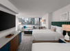 Two queen beds, a flat-screen TV, and a seating area inside a guest room.