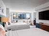 Two queen beds, a flat-screen TV, and a seating area inside a guest room.