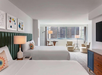 Two queen beds, a flat-screen TV, and a seating area inside a guest room.