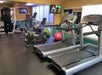 A gym with treadmills, an elliptical machine, exercise balls, and a TV on the wall.