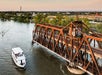 The Sacramento River: Alive After Five Cruise sailing past an old iron bridge at sunset with the city in the background.