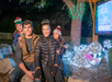 A smiling family of four poses outdoors at night near a tree decorated with holiday lights and a light-up hippopotamus display.
