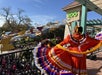 Performer in her festive colored costume in front of the new front entrance of San Antonio Zoo with the guests.