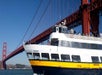 A passenger ferry named Old Blue sails under the Golden Gate Bridge in San Francisco on a clear day.