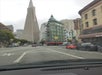 View from a car on a city street with the flatiron-shaped Sentinel Building and the Transamerica Pyramid in the background.