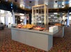 Two buffet bars full of food in an open room with a bar in the background on the San Francisco Lunch Cruise by Hornblower.