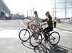 Two women riding bikes down the street on a sunny day while laughing with each other in Santa Monica.