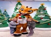 Two young children stand on either side of a person in a reindeer costume, posing in front of decorated Christmas trees.