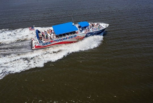 Aerial view looking down on a blue white and red Sea Thunder speed boat with its deck full of people on a sunny day.