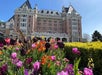 A large historic hotel building with "The Empress" sign, seen behind colorful blooming tulips and flowers on a sunny day.