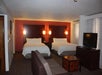 Two queen beds, seating area, and TV inside a guest room.