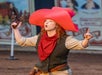 A woman with a gun in her hand in a cowboy suit.
