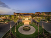Exterior view of a hotel at dusk, featuring a circular driveway and palm trees. The building is well-lit, with a clear sky in the background.