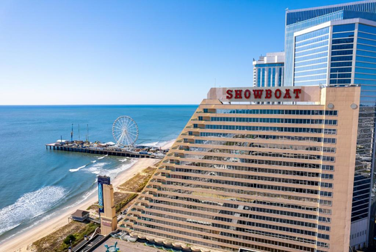 Aerial view of the Showboat hotel next to the beach, with a pier and ferris wheel in the background on a clear day.