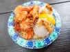 A paper plate of heavily seasoned shrimp with rice and fruit from Shrimp Trucks.
