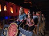 A woman and a young girl sit together on an amusement park ride at Silver Dollar City, surrounded by other riders, with themed decorations in the background.