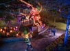 People walk past a large Halloween display featuring illuminated jack-o'-lanterns and a giant pumpkin spider, with colorful lights illuminating the scene at night.