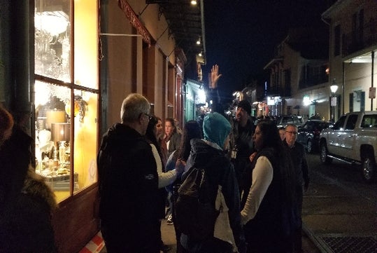 Guests enjoying one of the many stories told by the tour guide on the Tour guide dressed in black tells stories to guests on the Sinister Criminal Intentions Tour in New Orleans, LA.