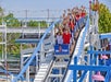 Guests laughing with their arms up riding the blue and white Little Dipper coaster on a sunny day with trees behind them at Six Flags.