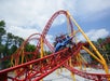 Guests having a good time riding the red and yellow Dare Devil Dive coaster with their arms up on a sunny day at Six Flags.