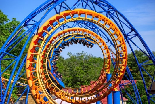 A group of park-goers going through the spiral of the Steamin' Demon on a sunny day at Six Flags Great Escape.