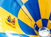 Three people ride a yellow inflatable raft down a large blue and yellow water slide at a water park.