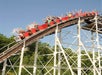 A large group of people excitedly raise their hands while riding the massive 4,200-foot wooden coaster, the Comet, as it hurtles downhill at Six Flags Great Escape.
