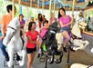 A group of people, including children and adults, ride carousel horses and smile at an amusement park during the daytime.