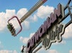 A thrill ride called "Catwoman Whip," with riders suspended high above the ground, enjoying an exhilarating experience against a backdrop of fluffy clouds.