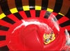 Aerial view of four people in a yellow tube on a red waterslide with black and yellow accents on a sunny day.