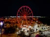 Aerial view of the SkyWheel in Panama City Beach at night with the lights on the wheel glowing red.
