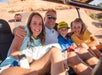 A family posing for the camera in the back of the Hummer while going up a steep hill on the Slickrock Safari Hummer Adventure Tour in Moab Utah.