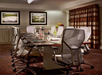 A conference room with a long table, eight chairs, notepads, bottles of water, fruit, and two framed landscape photos on the wall.