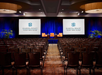 A conference room with rows of chairs facing a stage with two screens displaying the Sonesta Resort Hilton Head Island logo.