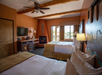 Two queen beds, a flat-screen TV, a fireplace and a private balcony inside a guest room.