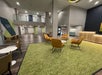 Lobby area with green carpet, modern chairs, a front desk, and a vending machine.