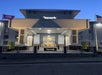 Hotel entrance at dusk with a sign reading "spark." The building has columns, lighting, and two flags on either side.