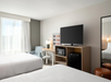 The room features two queen beds, a TV, mini-fridge, microwave, and a desk for comfort and convenience.
