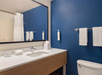 Private bathroom with mirror, sink, toiletries, and fresh towels.