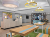 Modern lobby featuring a front desk, casual seating, and a self-serve refreshment area.